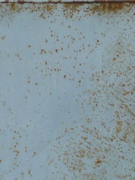 Grey metal door dotted with brown spots of rust.